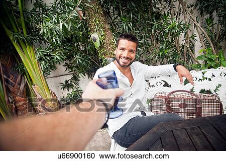Man toasting with friend on patio View Large Photo Image Stock Image - Man toasting with friend on patio. Fotosearch
