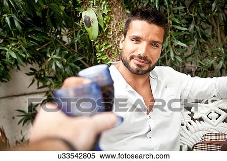 Man toasting with friend on patio View Large Photo Image Stock Photography - Man toasting with friend on patio. Fotosearch