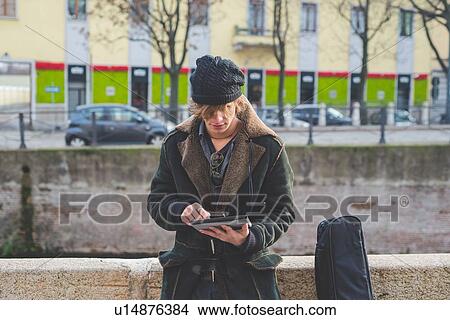 Picture - "Man using digital tablet by canal, Milan, Italy". Fotosearch