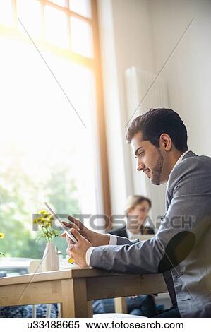 Man using digital tablet in cafe View Large Photo Image Stock Photography - Man using digital tablet in cafe. Fotosearch