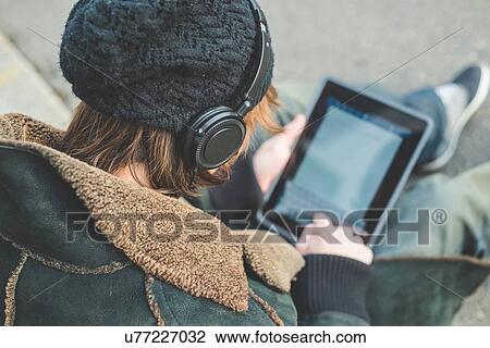 Stock Image - "Man using digital tablet on kerb, Milan, Italy". Fotosearch