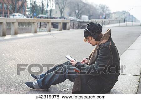 "Man using digital tablet on kerb, Milan, Italy" View Large Photo Image Stock Photo - "Man using digital tablet on kerb, Milan, Italy". Fotosearch
