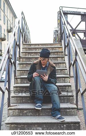 Stock Image - "Man using digital tablet on steps, Milan, Italy". Fotosearch