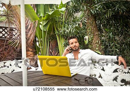 Stock Photography - Man using laptop on patio. Fotosearch