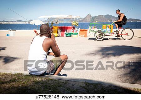 Stock Photo - Man watching water seller on bicycle. Fotosearch