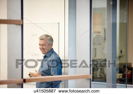 Stock Photo - Mature businessman presenting on office whiteboard. Fotosearch