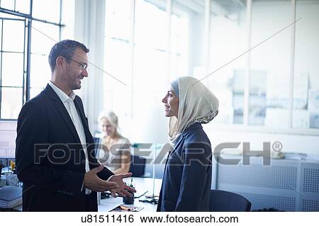 Mature businessman talking to young businesswoman in office View Large Photo Image Stock Photograph - Mature businessman talking to young businesswoman in office. Fotosearch