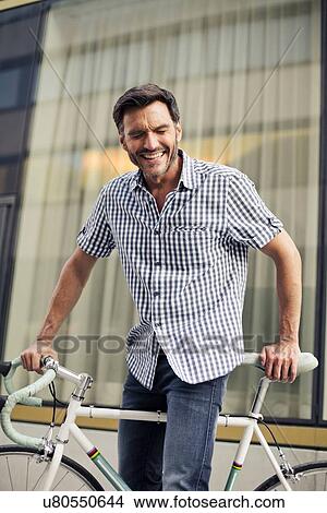 Mature male cyclist laughing on city street View Large Photo Image Picture - Mature male cyclist laughing on city street. Fotosearch