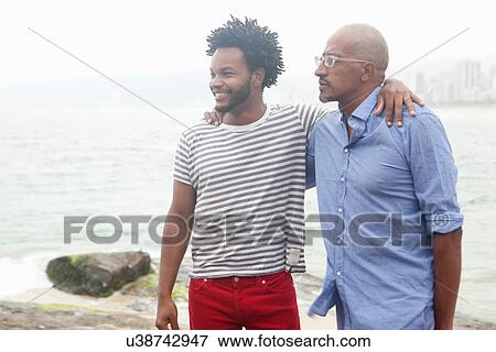 "Mature man and son with arms around each other, Ipanema beach, Rio De Janeiro, Brazil" View Large Photo Image Stock Photo - "Mature man and son with arms around each other, Ipanema beach, Rio De Janeiro, Brazil". Fotosearch