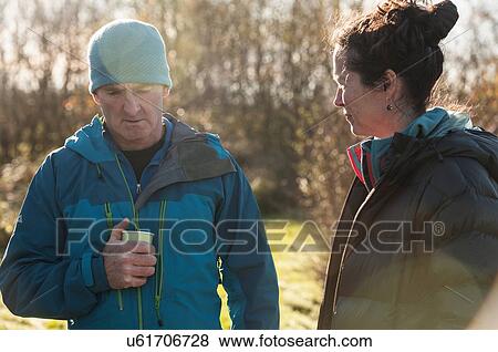 Stock Photo - Mature man and woman wearing coats in sunlight. Fotosearch
