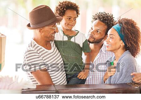Stock Photo - "Mature man chatting to family at beach bar, Ipanema beach, Rio De Janeiro, Brazil". Fotosearch