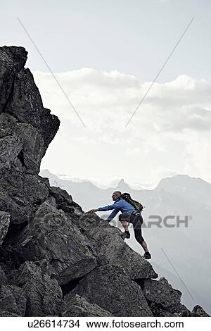 "Mature man climbing up rocks, Valais, Switzerland" View Large Photo Image Picture - "Mature man climbing up rocks, Valais, Switzerland". Fotosearch