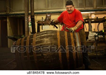 Stock Photo - Mature man making whisky cask in cooperage. Fotosearch