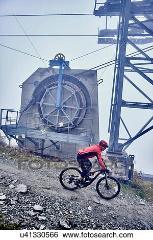 "Mature man mountain biking past cable car, Valais, Switzerland" View Large Photo Image Stock Photograph - "Mature man mountain biking past cable car, Valais, Switzerland". Fotosearch