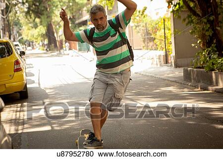 Stock Image - "Mature man skateboarding on street, Rio De Janeiro, Brazil". Fotosearch