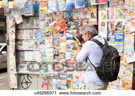 Stock Image - "Mature man taking photographs on street, Copacabana town, Rio De Janeiro, Brazil". Fotosearch