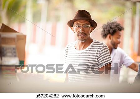 Stock Image - "Mature man wearing trilby at Ipanema beach, Rio De Janeiro, Brazil". Fotosearch