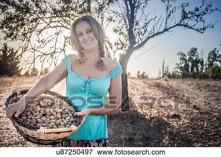 Mature woman holding basket in orchard View Large Photo Image Stock Photo - Mature woman holding basket in orchard. Fotosearch