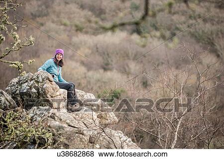 Stock Photo - "Mature woman sitting on rocks, portrait". Fotosearch
