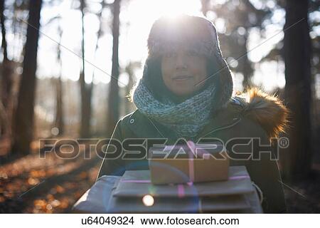 Picture - Mature woman walking through forest carrying gifts. Fotosearch