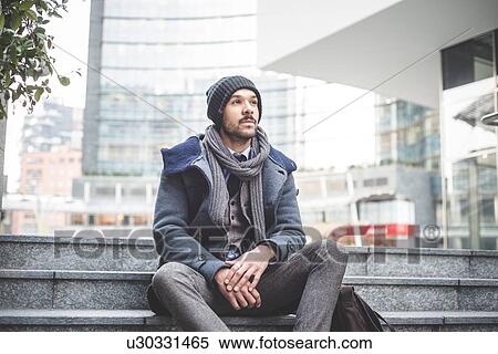 Stock Photography - Mid adult businessman sitting on office stairway. Fotosearch