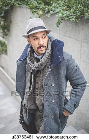 Stock Image - Mid adult businessman standing on stairway looking over his shoulder. Fotosearch