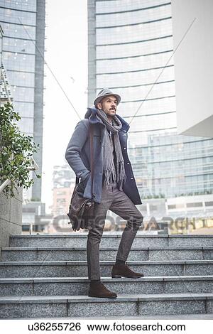 Stock Photograph - Mid adult businessman standing on stairway. Fotosearch