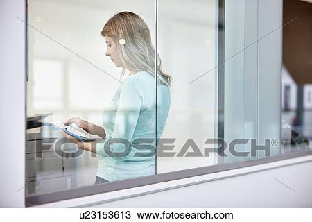 Mid adult businesswoman using digital tablet behind office window View Large Photo Image Stock Image - Mid adult businesswoman using digital tablet behind office window. Fotosearch