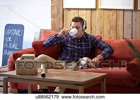 Mid adult man drinking coffee and petting dog in picture framers showroom View Large Photo Image Stock Photo - Mid adult man drinking coffee and petting dog in picture framers showroom. Fotosearch