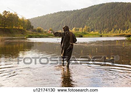 Stock Image - "Mid adult man fishing in river, Sarsy village, Sverdlovsk Region, Russia". Fotosearch