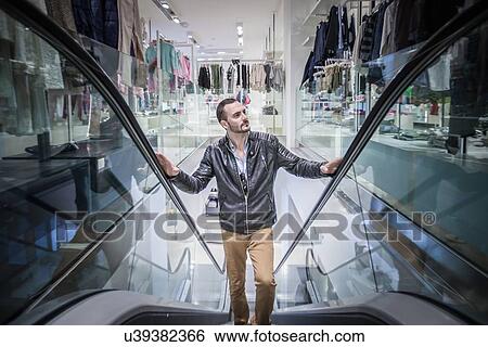 Mid adult man moving up escalator in shopping mall View Large Photo Image Stock Photograph - Mid adult man moving up escalator in shopping mall. Fotosearch
