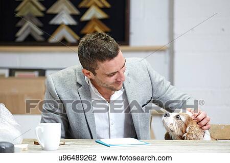 Mid adult man petting dog at desk in picture framers workshop View Large Photo Image Stock Image - Mid adult man petting dog at desk in picture framers workshop. Fotosearch