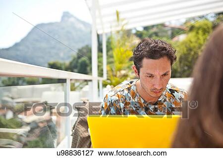 "Mid adult man sitting on balcony, using laptop" View Large Photo Image Stock Photo - "Mid adult man sitting on balcony, using laptop". Fotosearch
