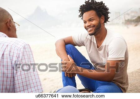 "Mid adult man sitting on Ipanema beach chatting to father, Rio De Janeiro, Brazil" View Large Photo Image Stock Image - "Mid adult man sitting on Ipanema beach chatting to father, Rio De Janeiro, Brazil". Fotosearch