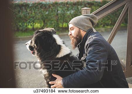 "Mid adult man sitting with dog, outdoors" View Large Photo Image Picture - "Mid adult man sitting with dog, outdoors". Fotosearch