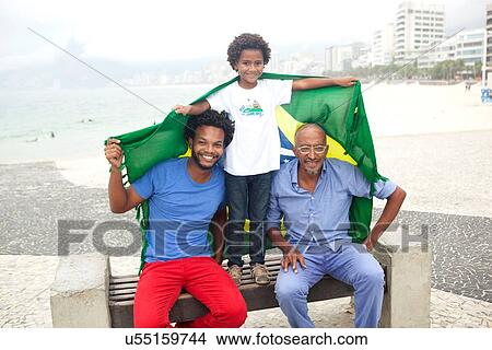 "Mid adult man with father and son holding up Brazilian flag on park bench, Ipanema beach, Rio De Janeiro, Brazil" View Large Photo Image Picture - "Mid adult man with father and son holding up Brazilian flag on park bench, Ipanema beach, Rio De Janeiro, Brazil". Fotosearch