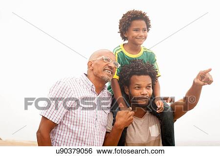 Stock Photograph - "Mid adult man with father and son pointing on Ipanema Beach, Rio De Janeiro, Brazil". Fotosearch