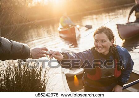Stock Photo - Mid adult woman giving her glasses to man. Fotosearch