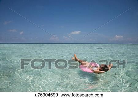 Stock Photo - "Mid adult woman on rubber ring in Indian Ocean, Maldives". Fotosearch