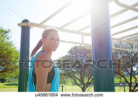 Picture - Mid adult woman preparing to train on monkey bars in park. Fotosearch