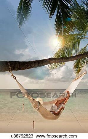 Stock Image - "Mid adult woman relaxing in hammock, Ari Atoll, Maldives". Fotosearch