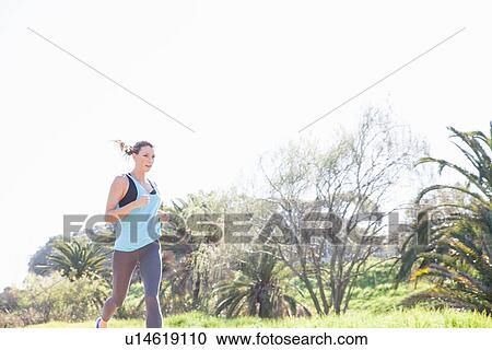 Mid adult woman running in park View Large Photo Image Stock Image - Mid adult woman running in park. Fotosearch