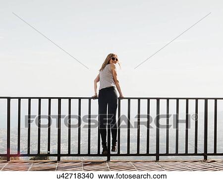 Stock Image - "Mid adult woman standing on balcony, looking at view, Mijas, Andalucia, Spain". Fotosearch