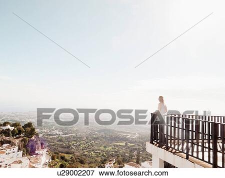 "Mid adult woman standing on balcony, looking at view, Mijas, Andalucia, Spain" View Large Photo Image Stock Photo - "Mid adult woman standing on balcony, looking at view, Mijas, Andalucia, Spain". Fotosearch