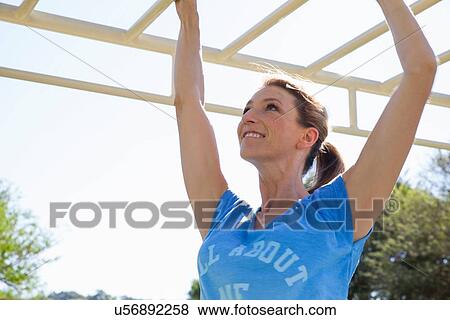 Mid adult woman training on monkey bars in park View Large Photo Image Stock Photo - Mid adult woman training on monkey bars in park. Fotosearch