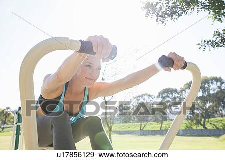 Mid adult woman training on rowing machine in park View Large Photo Image Stock Photo - Mid adult woman training on rowing machine in park. Fotosearch