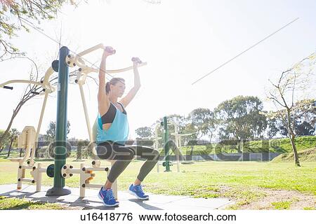 Mid adult woman training on weight machine in park View Large Photo Image Stock Photograph - Mid adult woman training on weight machine in park. Fotosearch