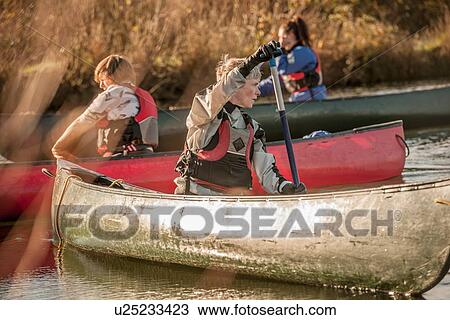 Mid adult woman turning around in canoe View Large Photo Image Stock Image - Mid adult woman turning around in canoe. Fotosearch