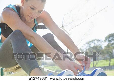 Mid adult woman tying trainer laces in park View Large Photo Image Stock Image - Mid adult woman tying trainer laces in park. Fotosearch