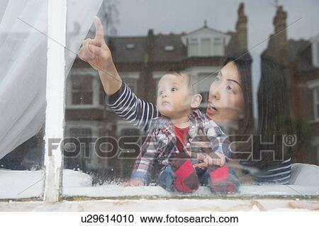 "Mother and baby boy looking out of window, view through window" View Large Photo Image Stock Image - "Mother and baby boy looking out of window, view through window". Fotosearch